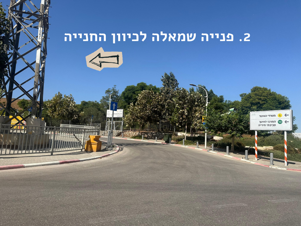 כביש עם הוראה לפנות שמאלה לכיוון החניה ושלט הכוונה