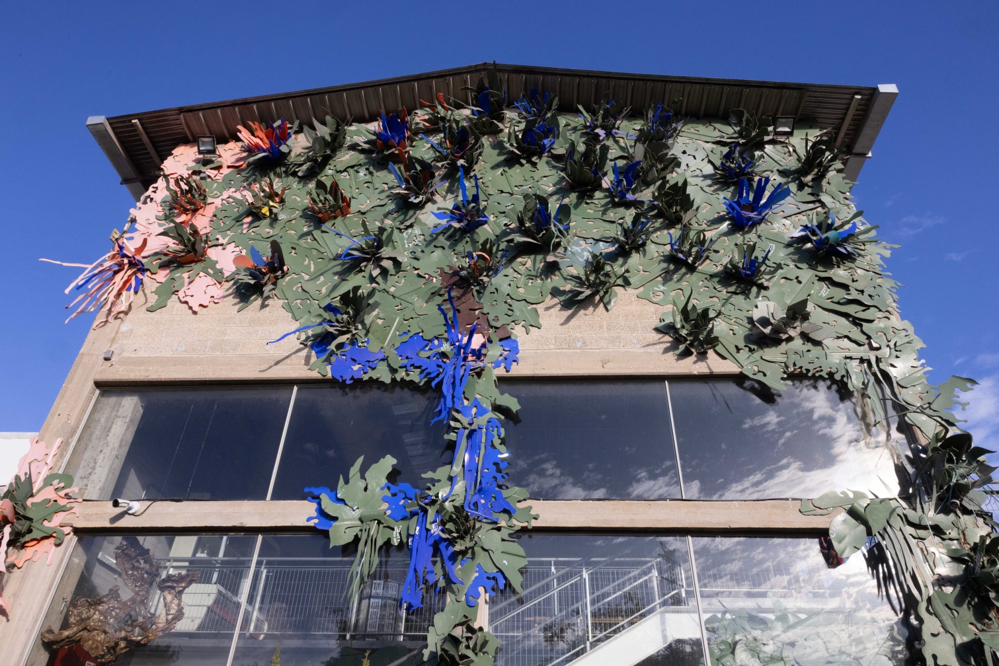 Colorful recycled-material leaf sculptures adorning a building facade